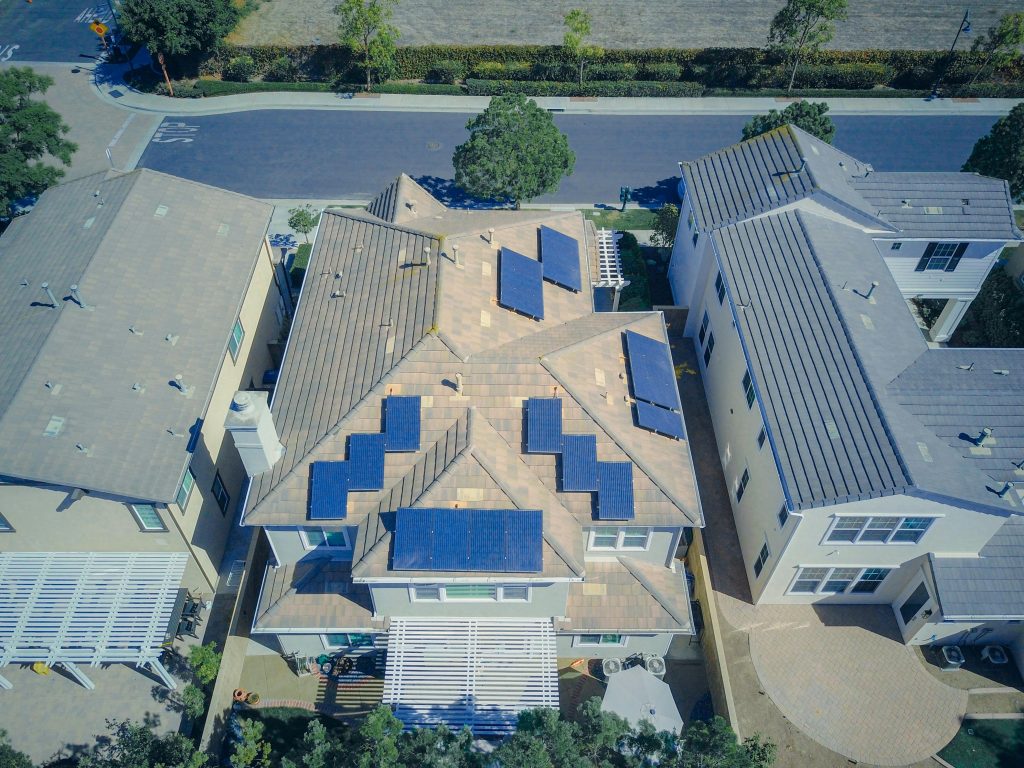 Aerial view of suburban homes equipped with solar panels in a sunny neighborhood.